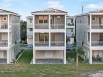 Three-story coastal home with screened balconies, gray siding, and manicured lawn at 4318 Marina View Way, Cortez, FL 34215