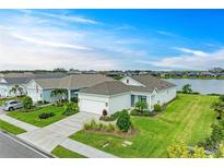 Inviting single-story home featuring lush landscaping, a two-car garage, and a tranquil lake view at 4625 Canoe Creek Ave, Parrish, FL 34219