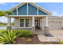 Inviting home entrance with stone accents, blue shingle siding, and charming front porch landscaping at 5240 Bentgrass Way, Bradenton, FL 34211