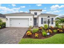 Charming single-story home with brick-paved driveway, two-car garage, and colorful front garden at 10423 Morning Marsh Ln, Parrish, FL 34219