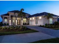 Elegant home exterior boasts a three-car garage, lush landscaping, and a paved driveway at 1198 Blue Shell Loop, Sarasota, FL 34240