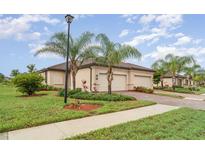 Charming home featuring a barrel tile roof, lush landscaping, and a paver driveway leading to a two-car garage at 12515 Garibaldi Ln, Venice, FL 34293