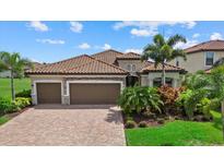 Charming home with a tile roof, a three-car garage, a brick paver driveway, and lush landscaping at 14216 Florida Rosemary Dr, Bradenton, FL 34211