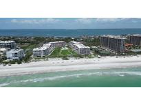 Stunning aerial view of beachfront condos with pristine beach, blue ocean, and well-manicured landscaping at 1445 Gulf Of Mexico Dr # 203, Longboat Key, FL 34228