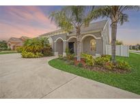 Beautiful gray home featuring an arched portico, lush tropical landscaping, and a circular driveway at 1905 Via Napoli St, Plant City, FL 33566