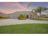Charming home featuring a three-car garage, a well-manicured lawn, and tropical landscaping at 1905 Via Napoli St, Plant City, FL 33566