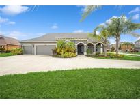 Charming home featuring a three-car garage, a well-manicured lawn, and tropical landscaping at 1905 Via Napoli St, Plant City, FL 33566