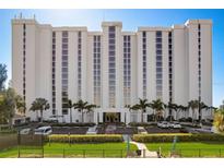 Modern condo building with a manicured lawn, palm trees, and parking spaces at 2425 Gulf Of Mexico Dr # 14B, Longboat Key, FL 34228