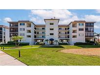 Beautiful condo with a well-manicured lawn, palm trees, and a blue awning covered entryway at 3630 Gulf Of Mexico Dr # 202, Longboat Key, FL 34228