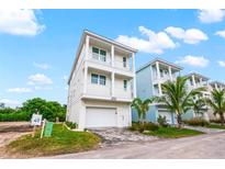 Charming three-story coastal home with white facade, dual balconies, and garage at 4321 Marina View Way, Cortez, FL 34215