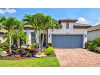 Charming single-Gathering home featuring lush landscaping, a brick driveway, and a two-car garage at 5740 Eagle Creek Rd, Sarasota, FL 34238