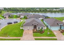 A house with a lush green lawn, brick driveway, two-car garage, and a serene lake in the background at 6636 35Th E Ct, Sarasota, FL 34243