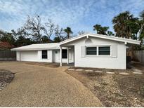 A charming single-story home with white exterior, gravel driveway, and minimal landscaping set against a cloudy sky at 782 Birdsong Ln, Sarasota, FL 34242