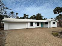 Charming single-story home featuring white paint, a two-car garage, and tropical landscaping with palm trees at 782 Birdsong Ln, Sarasota, FL 34242