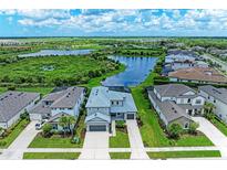 Breathtaking aerial view of a two-story home with a lake view and well-manicured landscaping at 8264 Summer Night Rd, Sarasota, FL 34241