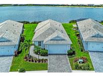 Beautiful home featuring an attached garage, tile roof, and lush landscaping with a scenic waterfront view at 909 Crosswind Ave, Sarasota, FL 34240