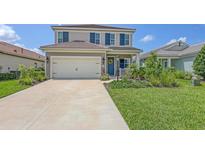 Charming two-story home with a well-manicured lawn, shutters, and a two-car garage at 12708 Aquamarine Ave, Bradenton, FL 34211