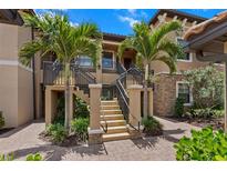 Inviting condo exterior showcasing landscaped entry with palm trees and a charming stairway leading to the upper level entrance at 13810 Messina Loop # 202, Bradenton, FL 34211