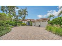 Beautiful exterior with a brick driveway, barrel tile roof, lush landscaping and three-car garage at 1864 Goldenrod St, Sarasota, FL 34239
