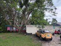 Whimsical cottage-style home with pink accents, mature trees, and a vintage car parked in front at 5011 Elfrida Ave, Sarasota, FL 34235