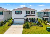 Charming two-story home featuring a landscaped yard, covered porch, and two-car garage at 5644 Flagstone Trl, Palmetto, FL 34221