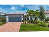 Charming single-story home featuring a paver driveway, lush landscaping, and a neutral color palette at 6714 Alstead Cir, Bradenton, FL 34202