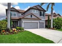 Charming two-story home featuring a gray stucco exterior, red tile roof, and meticulously landscaped front yard at 7020 Island Queen Ct, Sarasota, FL 34233