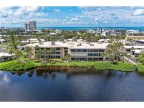 Waterfront condo complex featuring palm trees, lush greenery, and stunning water views at 101 Whispering Sands Dr # 307, Sarasota, FL 34242