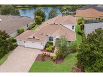 Aerial view of a well-maintained home with a three-car garage, landscaped yard, and waterfront access at 12031 Longview Lake Cir, Lakewood Ranch, FL 34211