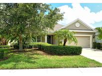 Charming single-story home featuring a manicured lawn, lush landscaping, and an attached two-car garage at 12331 Halfmoon Lake Ter, Bradenton, FL 34211