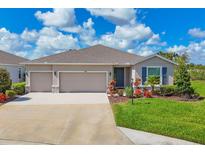 Charming home featuring a three-car garage and a well-maintained lawn with colorful landscaping at 16606 Barnwood Pl, Lakewood Ranch, FL 34211