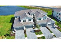 A view of two-story townhomes featuring gray roofs and driveways, with attached garages and well-manicured lawns at 17715 Boracay Ct # 202, Venice, FL 34293