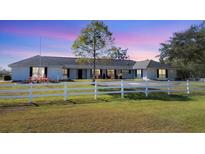 Home with a circular driveway, white fence, and green grass with the sky turning from dusk to night at 2005 21St W St, Palmetto, FL 34221