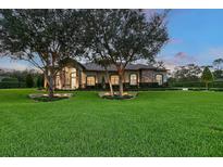 Stunning single-story home with a beautiful stone and stucco facade, mature trees, and a well-manicured lawn at 22343 Panther Loop, Bradenton, FL 34202