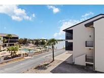 Attractive exterior view of condo complex featuring a waterfront pool area, palm trees, and well-maintained landscaping at 2729 North Beach Rd # 212, Englewood, FL 34223
