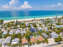 Stunning aerial view of beachfront homes near the ocean with white sand and clear blue water on a sunny day at 3016 Gulf Dr, Holmes Beach, FL 34217