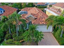 Stunning aerial view of a tile roof home with lush landscaping, pool and a paved driveway at 303 9Th E Ave, Palmetto, FL 34221