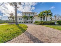 Charming two-story home boasts a brick driveway and lush tropical landscaping, creating a welcoming curb appeal at 634 Key Royale Dr, Holmes Beach, FL 34217