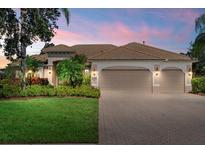 Charming single-story home with a well-maintained lawn, beautiful landscaping, and a beige tile roof at 6528 Coopers Hawk Ct, Lakewood Ranch, FL 34202