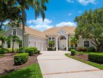 Stately home with a clay tile roof, three-car garage and a circular driveway with mature landscaping at 7003 Lancaster Ct, University Park, FL 34201