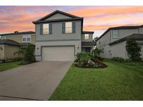 Charming two-story home featuring a manicured lawn, attached garage, and attractive landscaping at 8815 Windlass Cv, Parrish, FL 34219