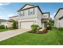 Charming two-story home featuring a manicured lawn, attached garage, and attractive landscaping at 8815 Windlass Cv, Parrish, FL 34219
