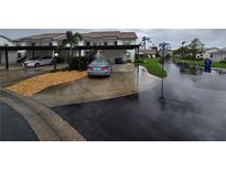 Exterior of condo featuring covered parking, landscaping, and street view on a rainy day at 1211 Capri Isles Blvd # 116, Venice, FL 34292