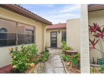 Inviting front entrance with tiled walkway and lush landscaping leading to the front door at 1227 56Th St W # 1227, Bradenton, FL 34209