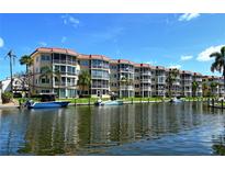 Waterfront condominium featuring boat slips, lush landscaping, and a serene canal view under a clear blue sky at 1250 N Portofino Dr # 208, Sarasota, FL 34242