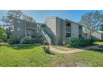 Inviting two-story condo with well-maintained landscaping, walkway, and staircase to the upper units at 137 Woodland Pl, Osprey, FL 34229