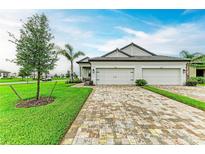 Charming two-story home showcasing a three-car garage, brick driveway, and beautifully landscaped front yard at 17898 Cherished Loop, Bradenton, FL 34211