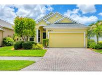 Charming yellow single-story home with a well-manicured lawn and brick driveway, showcasing curb appeal at 2085 Mattamy Ct, Venice, FL 34292