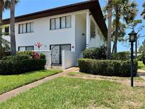 Inviting two-story condo with white exterior, brown trim, lush landscaping, and an iron gate entry at 3500 El Conquistador Pkwy # 347, Bradenton, FL 34210