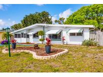 Charming single-story home featuring awnings, tidy landscaping and decorative rock features on a bright, sunny day at 4528 58Th W St, Bradenton, FL 34210
